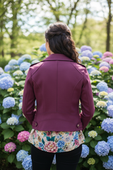 Model achterkant elegante pose met bordeauxrode bikerjack, hortensia achtergrond