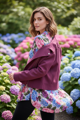 Model achterkant over schouder kijkend met bordeauxrode bikerjack, hortensia achtergrond